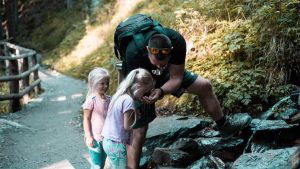 Father with daughters exploring nature on a forest path during a hike.