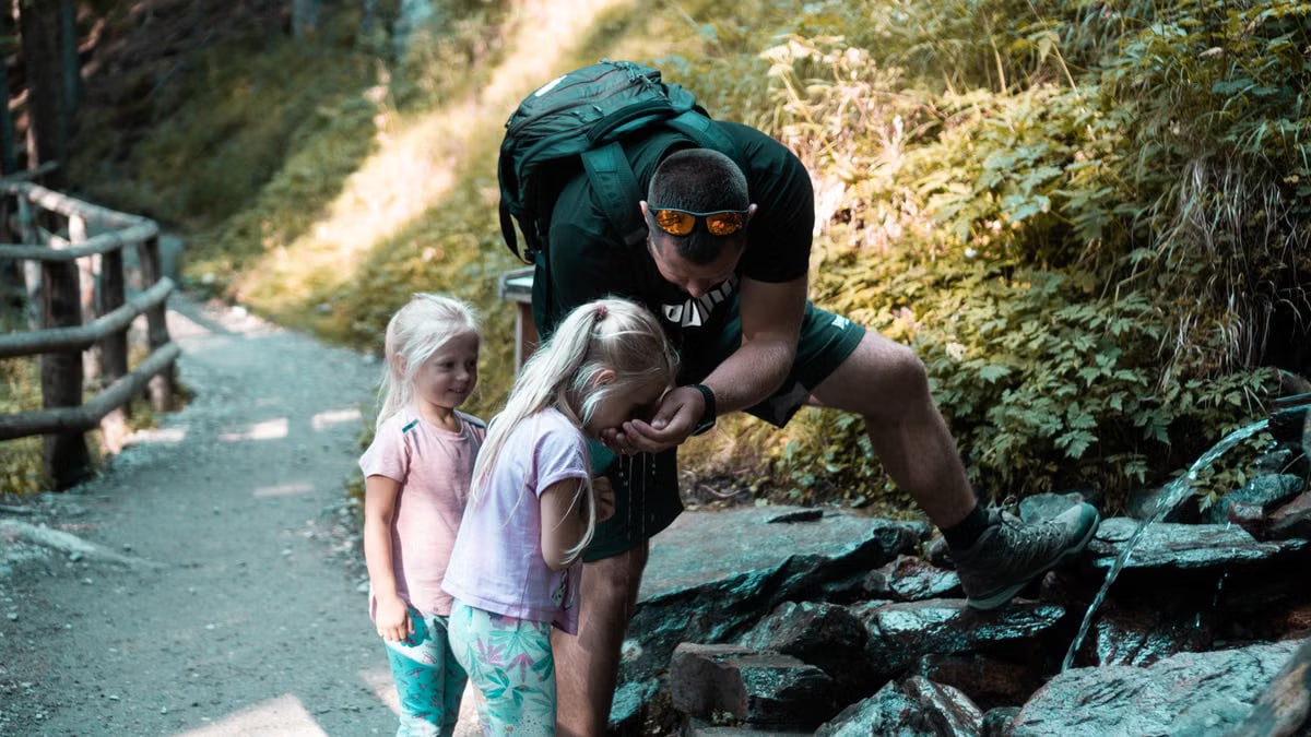 Father with daughters exploring nature on a forest path during a hike.