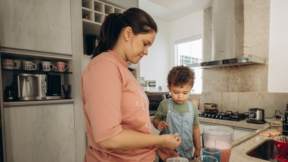 a woman standing next to a child in a kitchen